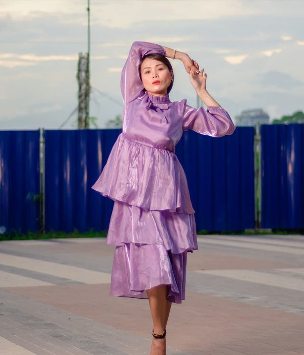 Woman in a graceful yoga pose against a soft purple background.